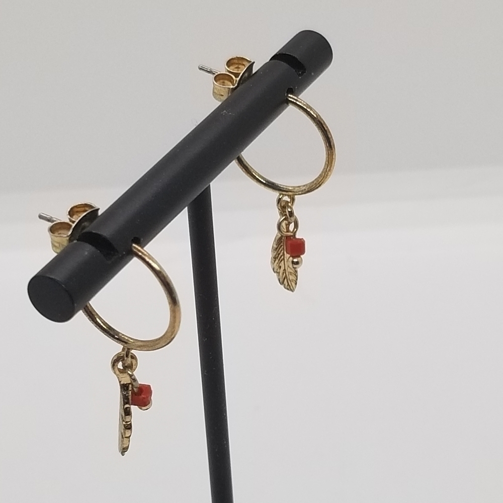 gold tone hoop earrings with feather charm and red bead